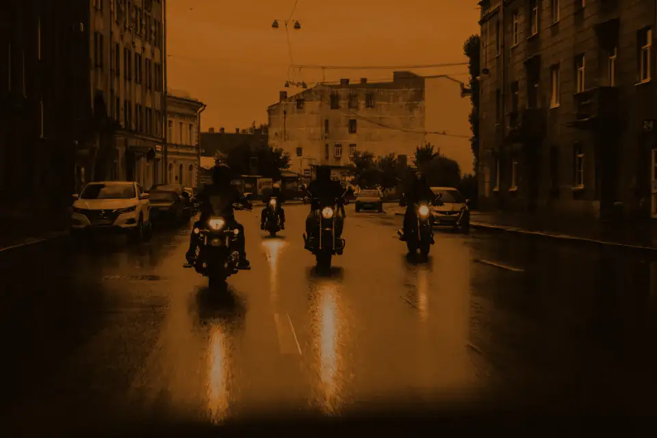Three motorbikes riding down a wet street